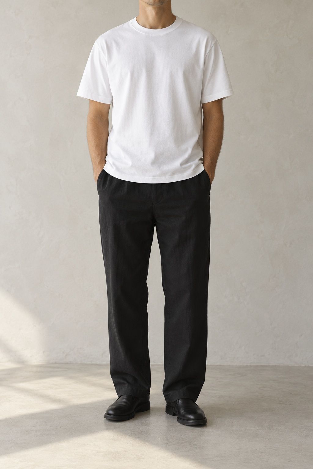 Sund cotton tee in white, worn and cropped at the chin, against a pale plaster wall